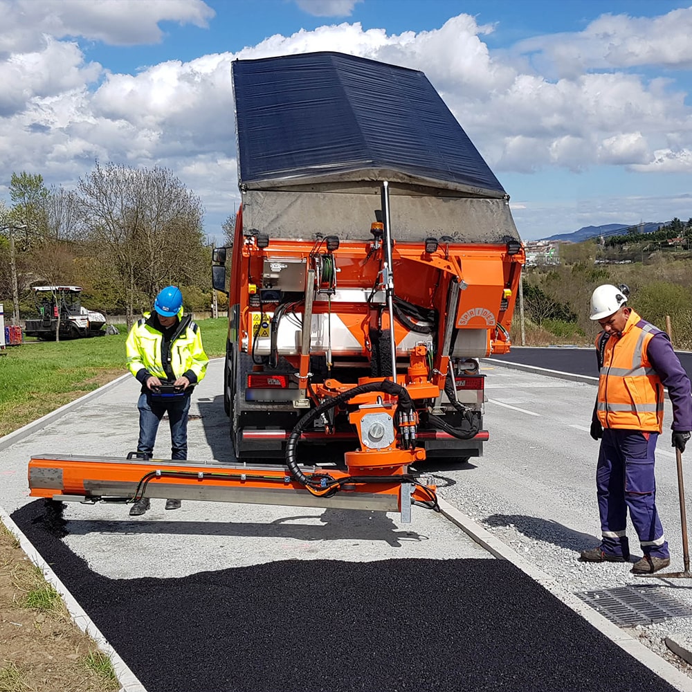 Sprider Asphaltmaschine, 2 Menschen verlegen Asphalt auf der Straße