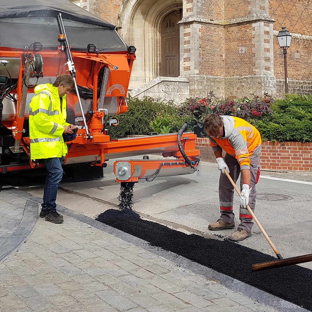 Sprider Asphaltmaschine, 2 Menschen verlegen Asphalt auf der Straße